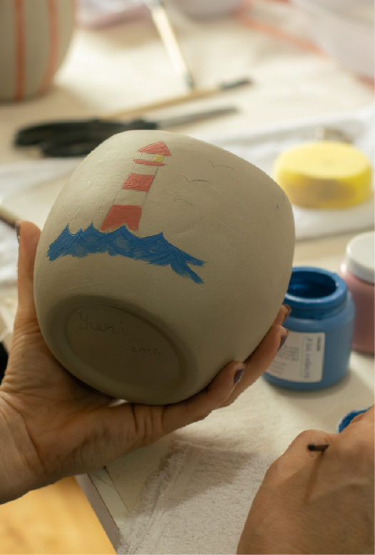 Participante pintando pinceladas azules con pincel sobre una pieza de cer&aacute;mica